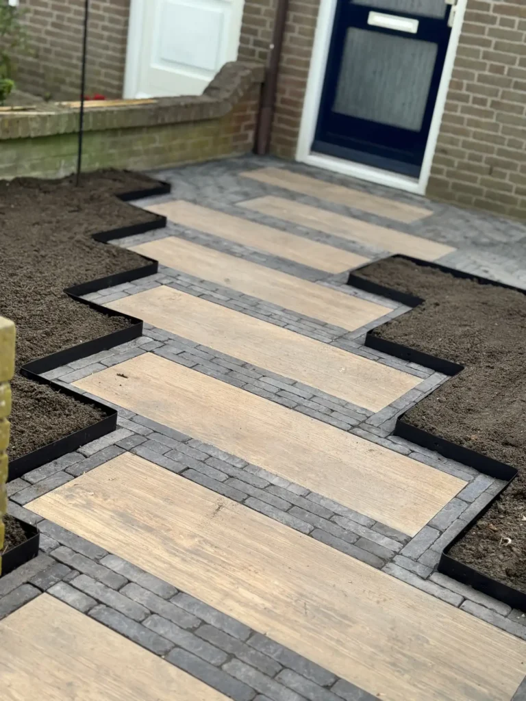 Voortuinpad van lichte tegels met antraciet borderranden en klinkers bij de entree van een woning