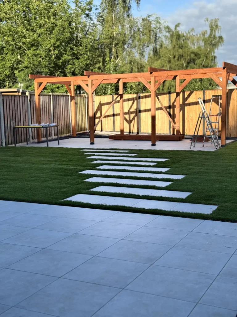 Houten pergola in aanbouw in een achtertuin met schutting, gazon en stapstenen pad